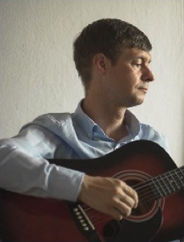 Piotr Bielski, guitar teacher at Unisono Music Academy in Warsaw, playing an acoustic guitar
